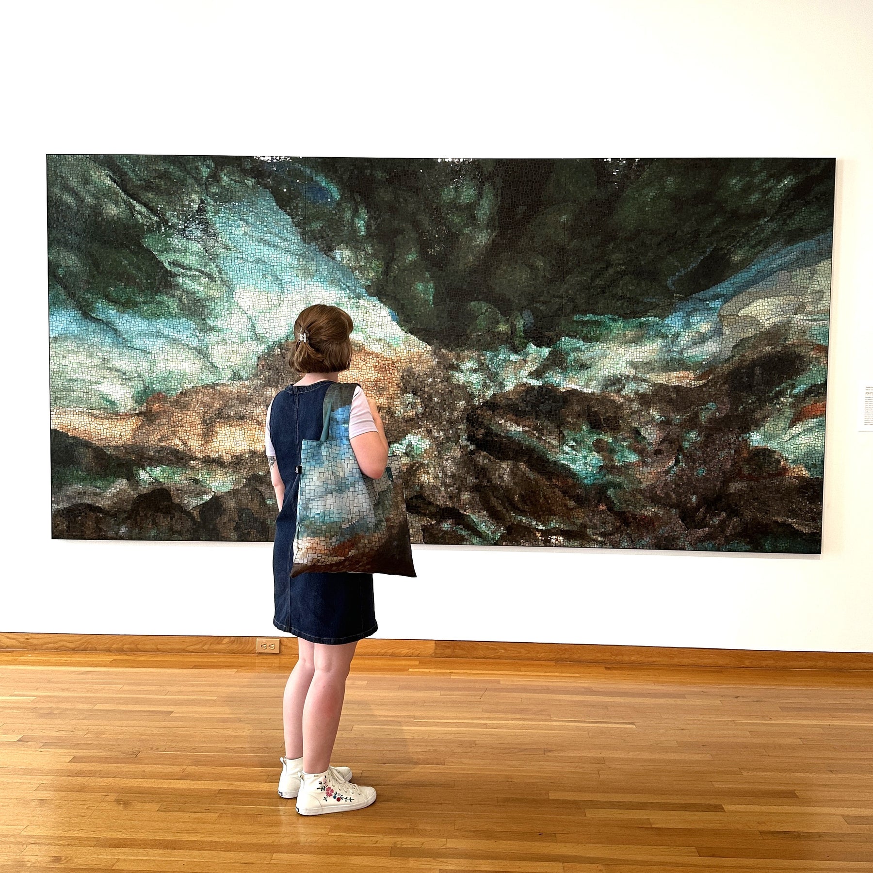 Person standing in front of a large abstract painting in an art gallery.