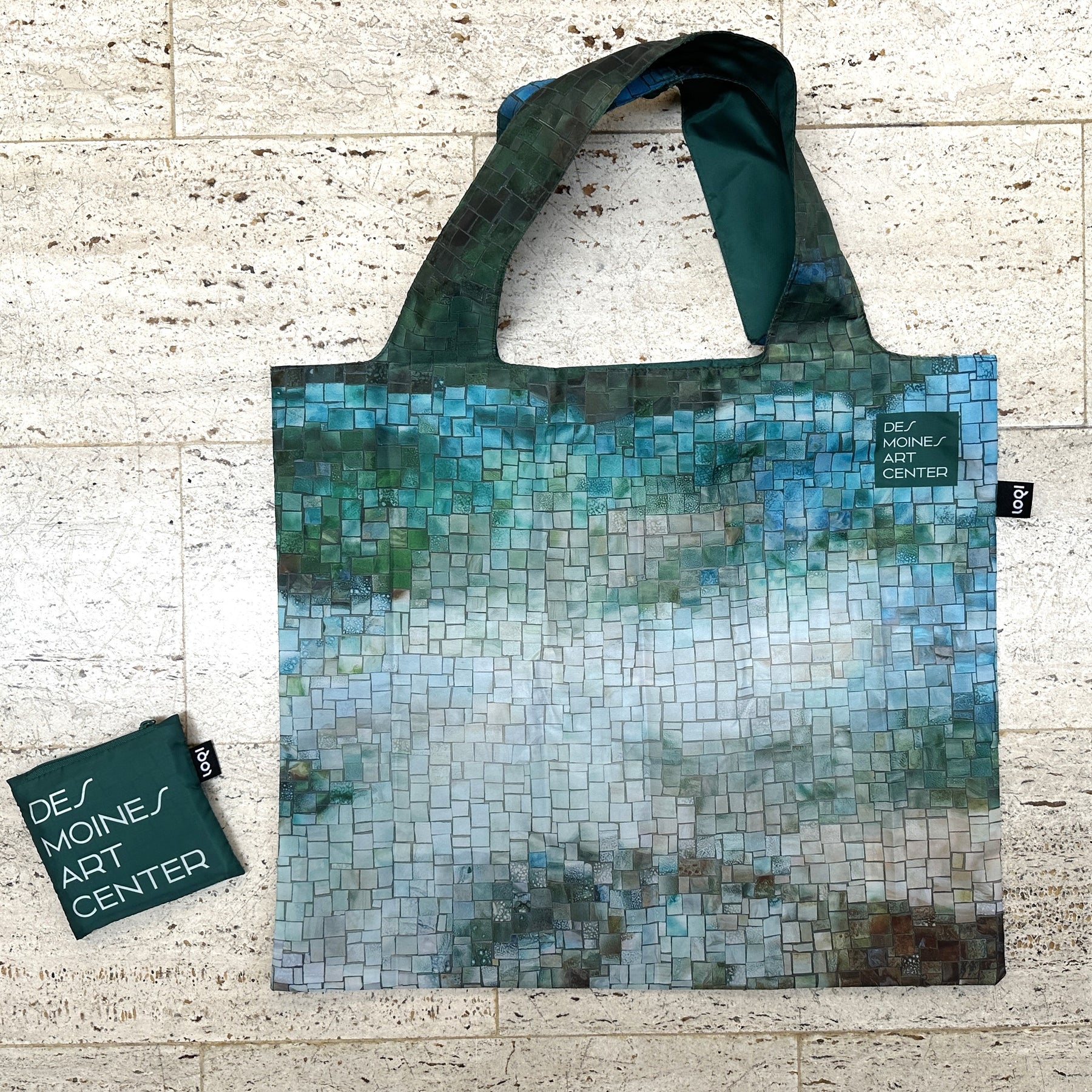 Tote bag with mosaic design and Des Moines Art Center branding on a textured surface